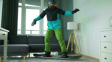 divertido video. hombre vestido como un snowboarder paseos un tabla de snowboard en un alfombra en un acogedor habitación video