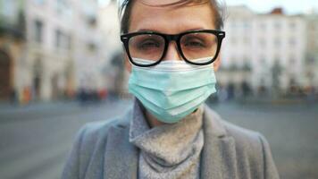 Pandemic protection of the Covid-19 coronavirus. Portrait of a woman in a coat, glasses and a protective medical mask. Glasses fog up from breath video