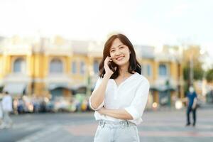 Portrait beautiful young asian woman with smart mobile phone around outdoor street view in a summer day photo