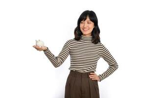 retrato de joven asiático mujer casual uniforme participación blanco cerdito banco aislado en blanco fondo, financiero y banco ahorro dinero concepto foto