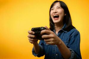 retrato joven asiático mujer con contento éxito sonrisa vistiendo mezclilla ropa participación palanca de mando controlador y jugando vídeo juego. divertido y relajarse pasatiempo entretenimiento estilo de vida concepto. foto