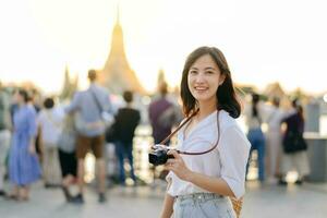 retrato joven hermosa asiático mujer sonriente mientras viaje a wat arun puesta de sol ver punto, bangkok, tailandia foto