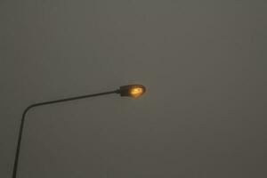 Electric lamps and electric poles in the rainy and stormy winter The fog is very thick, almost invisible, except for the electric pole and the gray sky background. photo