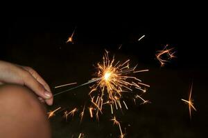 Fireworks light up the little girl's hand on a black background at night with Christmas celebrations around the world and festivals. photo