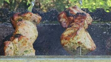 Grilled baked meat strung on skewers is grilled with hot coals and smoke. The skewers spin automatically. video