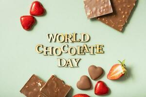 World chocolate day text with chocolate flat lay, top view on pastel green background photo