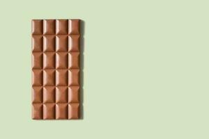 Chocolate bar flat lay, top view on pastel green background with copy space photo