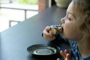 A little girl eats a donut in a cafe. Enjoying sweet food photo