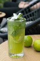 Fresh mojito and limes on a street cafe table. Summer cooling alcohol cocktail photo