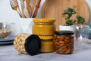 vaso frascos con miel y nueces. Almendras y avellanas en miel en cocina interior foto