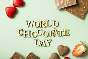 World chocolate day text with chocolate flat lay, top view on pastel green background photo