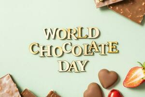 World chocolate day text with chocolate flat lay, top view on pastel green background photo