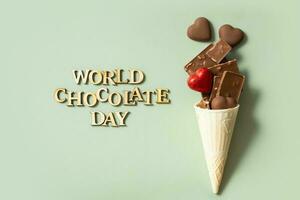 World chocolate day text with chocolate flat lay, top view on pastel green background photo