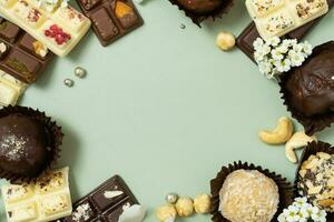 Frame made from craft chocolate candies, mini chocolates and nuts flat lay, top view photo
