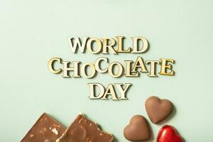 World chocolate day text with chocolate flat lay, top view on pastel green background photo