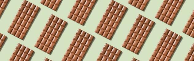 Chocolate bar pattern flat lay, top view on pastel green background photo