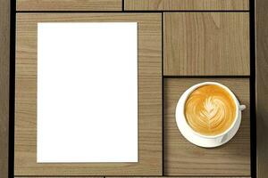 Poster next to coffee latte cup on a wooden coffee table surface photo