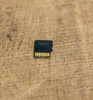 Detailed micro SD card on a wooden table. Micro SD card back side close up shot on a wooden surface. Memory card close up shot on a wooden surface. Action camera accessories and memory card. photo