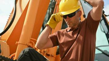 pesado construção equipamento caucasiano operador vestindo amarelo Difícil chapéu para uma cabeça segurança. escavadora ou rastejante operador às trabalhar. industrial tema. video