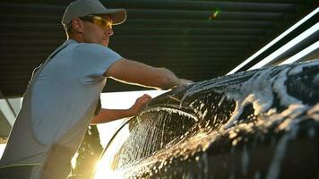 Man Washing His Car with a Sponge During Sunset video