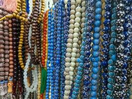 Plastic rosary market view. Colorful plastic rosaries close up shot in the market. Religious beads with colorful strings. Beautiful Muslim prayer beads close up view. Colorful chaplets for prayers. photo