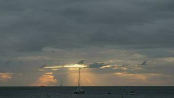 Golden rays of the sun through dark clouds, time lapse. Yachts floating near the shore. Tourism and travel concept video