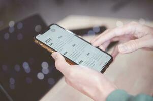 Concept of time management financial planning and reminder for 2024. man using smartphone working with calendar 2024, business planning marketing and investment, schedule appointment meeting photo