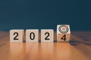 wooden cubes with the text  2024 and virtual arrow dart board  over background photo