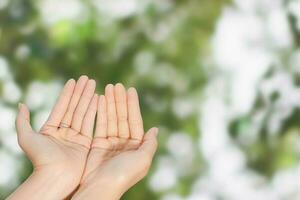 Closeup of woman open two empty hands with palms up for pray to God and blessing on green blur background photo