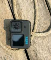 Dhaka, Bangladesh - March 12, 2023, GoPro 11 on a wooden table and with rope. Professional action camera close-up shot in the outdoor area. GoPro 11 black edition camera with rope and wooden surface. photo