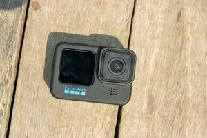 Barisal, Bangladesh - March 12, 2023, Modern action camera on a wooden surface. Professional action camera close up shot on a sunny day. GoPro 11 action and video cam with a black body. photo