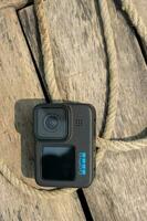 Barisal, Bangladesh - March 12, 2023, Modern action camera with rope on a wooden surface. GoPro 11 action and video cam with a black body. Professional action camera close up shot on a sunny day. photo