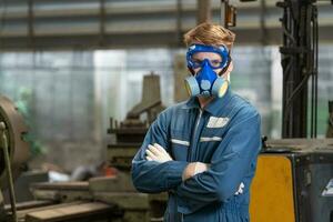 emergency pollution factory concept. Portrait engineer wearing a mechanical jumpsuit and gas mask looking at the camera with his arms crossed. photo