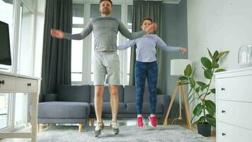 Caucasian couple is doing jumping jacks exercise at home in cozy bright room video