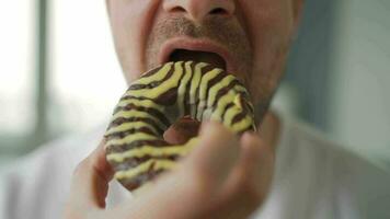 Man eating sweet chocolate donut. Close-up video
