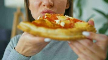 Woman eating pizza. Close-up. Concept of quick bites and unhealthy food video