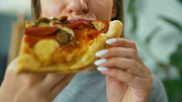 Woman eating pizza. Close-up. Concept of quick bites and unhealthy food video