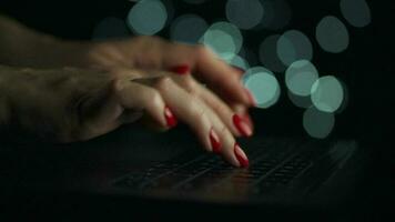 Female hands is typing on a laptop at night. Blurred lights on the background video