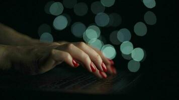 Female hands is typing on a laptop at night. Blurred lights on the background video