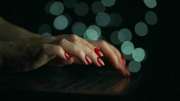 Female hands is typing on a laptop at night. Blurred lights on the background video