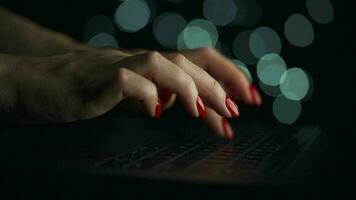 Female hands is typing on a laptop at night. Blurred lights on the background video