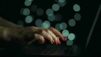 Female hands is typing on a laptop at night. Blurred lights on the background video