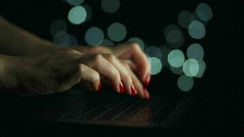 Female hands is typing on a laptop at night. Blurred lights on the background video