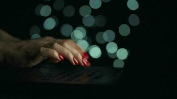 Female hands is typing on a laptop at night. Blurred lights on the background video