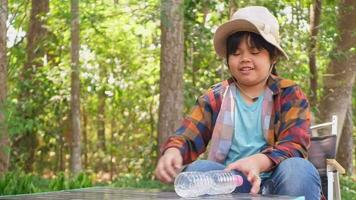 asiático niña sentado debajo el árbol sonriente felizmente video