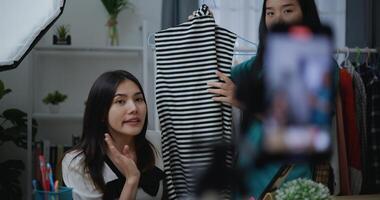 joven asiático hembra Moda diseñador utilizando móvil teléfono En Vivo humeante foto