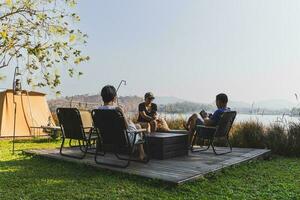 Three best friends sitting at camping nature outdoors using mobile phone. photo