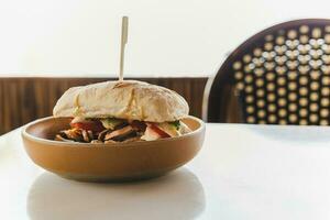 Chicken and cheese panini sandwich with fresh tomato on table. photo