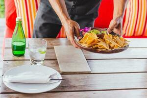 Waiter serving mexican nachos chips guacamole dip. photo