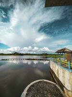 view of the lake dam in the afternoon with blue clouds in the background photo